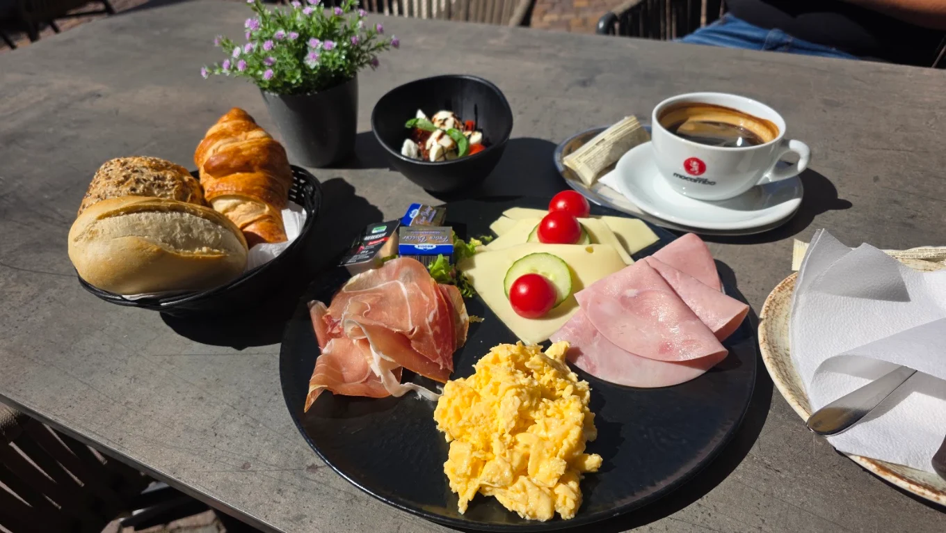 Reichhaltiges Frühstück mit Rührei, Brötchen und Kaffee